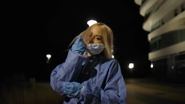 Cheerful Young Female Surgeon Takes Off Medical Mask During Night Shift
