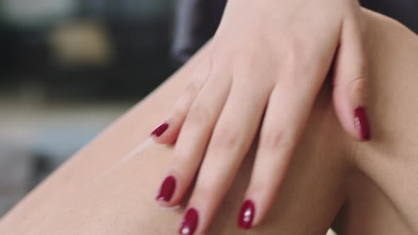 Woman Applying Body Moisturizer On Legs