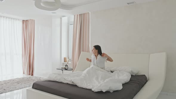 Beautiful Young Woman Waking Up In Modern Light Bedroom