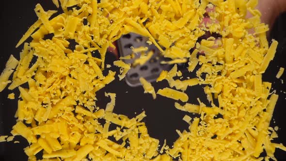 Grated cheese falls onto a glass surface. Bottom view.