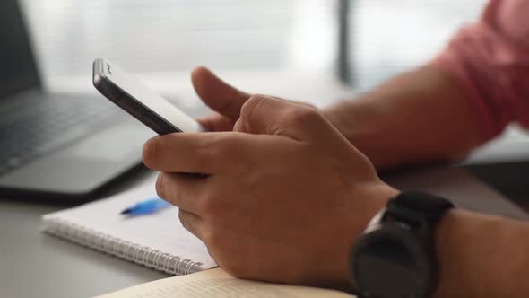 Closeup Hands of Unrecognizable Focused Businessman Using Mobile Phone Sitting at Desk with Laptop