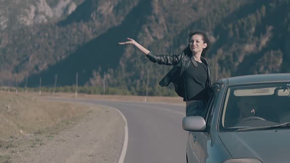 Elated Lady Sits on Blue Speeding Car and Raises Hand To Sky