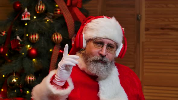 Portrait of Santa Claus Dancing Funny in Big Red Headphones