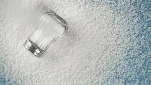 Super Slow Motion Drop Salt on a Salt Shaker on a Blue Background