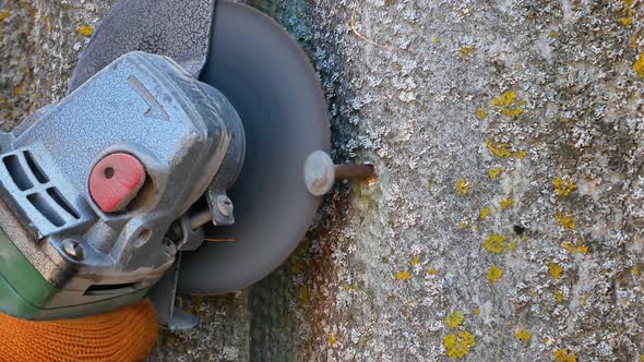 Cutting an iron nail with an electric grinder disc. 