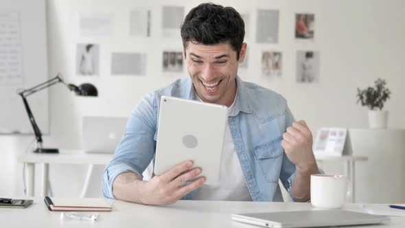 Casual Young Man Excited for Results on Tablet