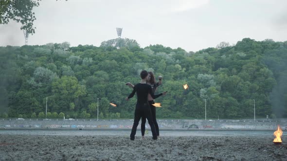 Young Beautiful Girl and Handsome Man in Black Clothes Performing Show with Flame Standing On