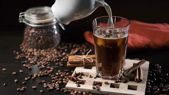 Pouring Milk From Jar Into Glass with Iced Coffee