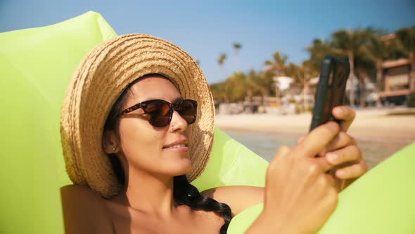 Attractive Woman Texting on Mobile Phone and Relaxing on Inflatable Mattress in Sea. Slowmotion