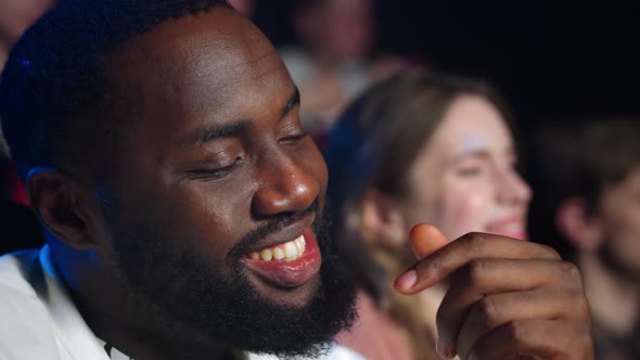 Happy African Man Laughing in Cinema. Joyful Afro Guy Eating Popcorn in Hall.