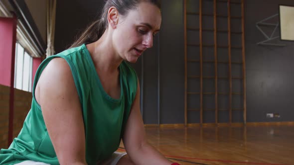 Caucasian female basketball player resting and holding ball