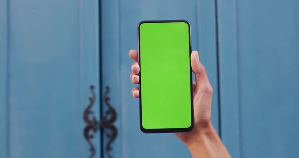 Close Up View of Female Hand Holding Smartphone with Blank Green screen . Concept of Mockup