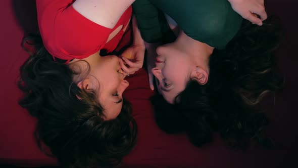 lesbians in love- women lying on the bed tenderly look into each other's eyes