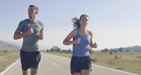 Tracking Slow Motion Shot of Sportive Couple Jogging Outdoors in the Morning Trail Running