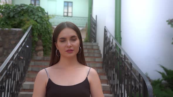 Charming girl on the street of the old town looks at the camera.