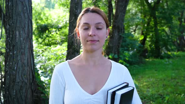 Young Woman Standing Alone in Park Smiling Looking at Camera. People and Style Concept.