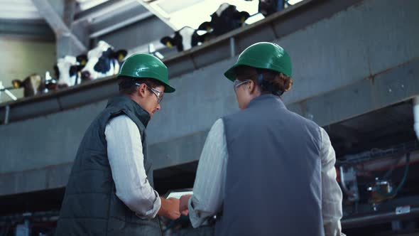 Livestock Specialists Working Automatic Milking Machinery with Tablet Computer