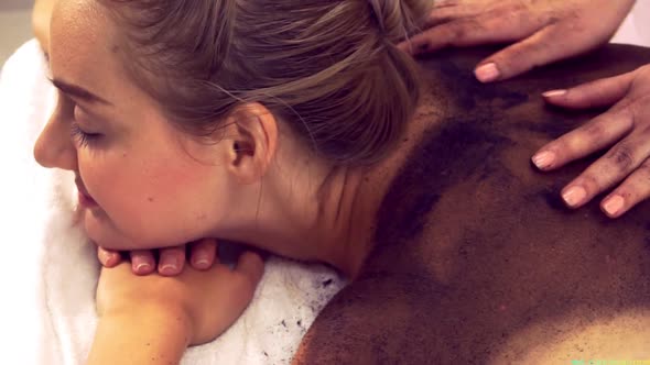 Relaxed Woman Lying on Spa Bed for Body Scrubbing Massage Using Traditional Herb