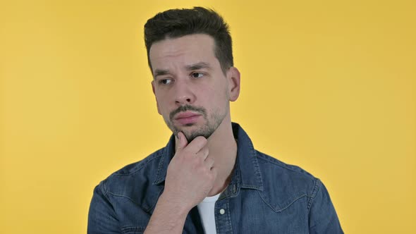 Portrait of Attractive Young Man Thinking and Getting Idea, Yellow Background