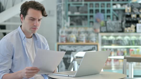 Young Man with Laptop Having Loss on Documents