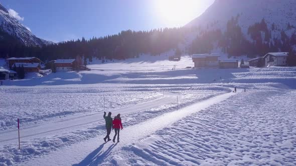 Aerial drone view of a man and woman couple walking in the snow at a ski resort