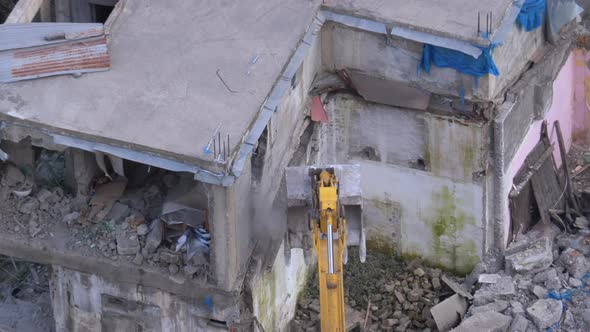 Destroying Old House Using Bucket Excavator on Construction Site alt
