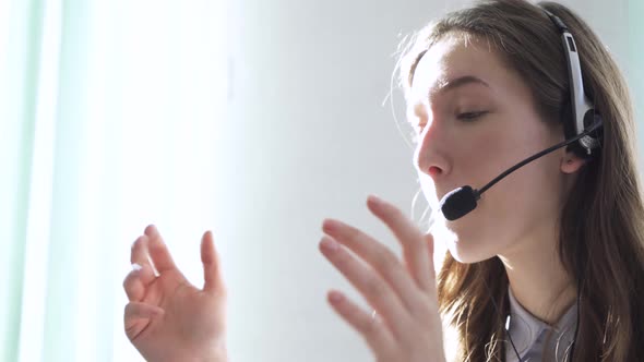 Young Woman Wearing Headphones Communicating Online Via Laptop Explaining Teaching