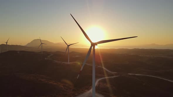 Wind turbines with blades in wind farm aerial view bright orange sunset