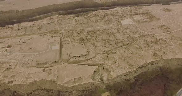 A drone shot moving backward of the ruins of Jiaohe, Xinjiang, by a grey day.