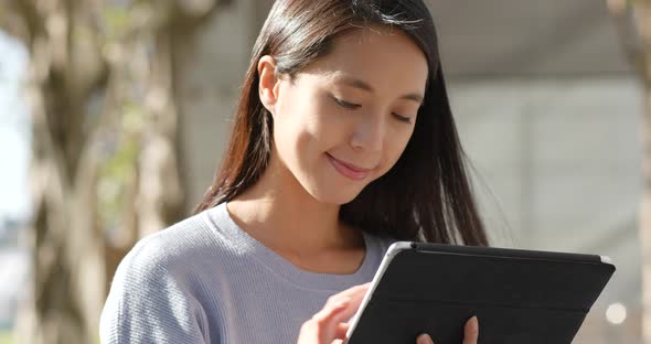 Woman working on tablet computer under sunlight