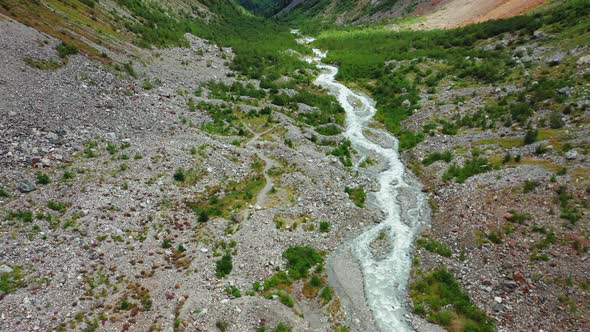 Aerial View of a Stormy Mountain Stream Among Multicolored Stones and Bushes