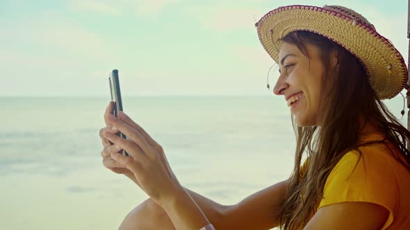 Side View Woman in Hat at Beach Using Smartphone Online Chatting Browsing on Internet