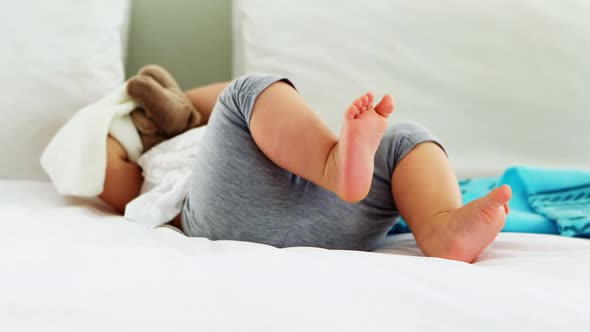 Cute baby girl playing with soft toy on bed