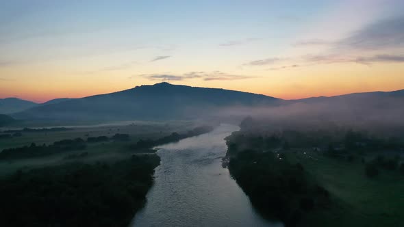 Fog over the river in the mountain valley. Landscape during sunset. View from the air.