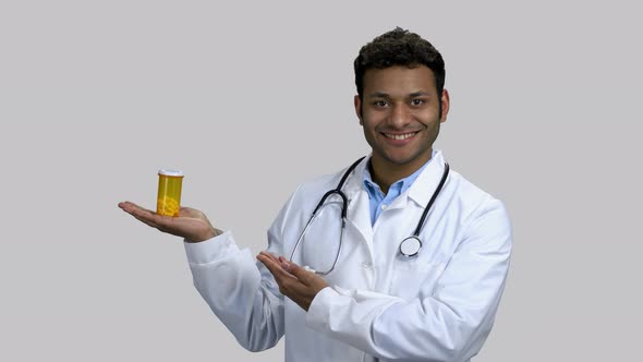 Young Darkskinned Doctor Advertising Can of Pills