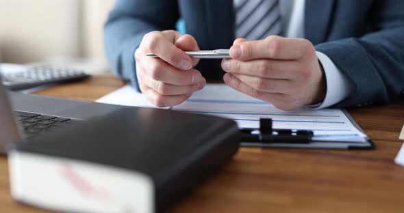 Businessman in Formal Suit Holds Pen While Sitting at Desk