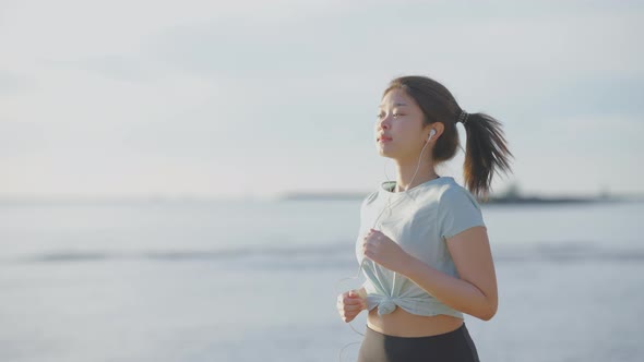 Asian cute girl She was jogging in the morning by the sea and the sun was shining. 4k resolution.