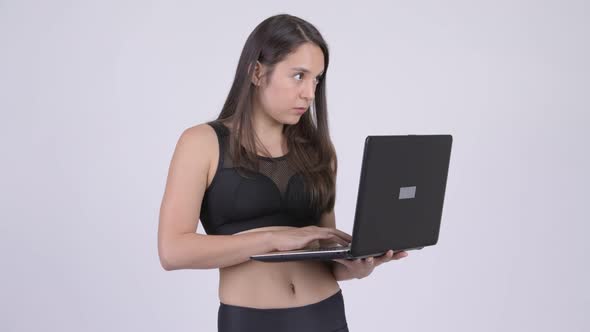 Young Happy Multi-ethnic Woman Thinking While Using Laptop Ready for Gym