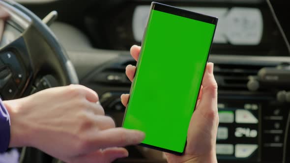 Close Up Woman Hand of the Driver in Car Uses a Smartphone with a Green Screen Inside a Car