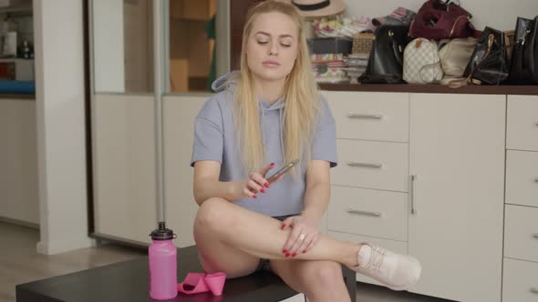 Shot of Beautiful Sporty Caucasian Woman Sitting on Table Using Smartphone After Workout