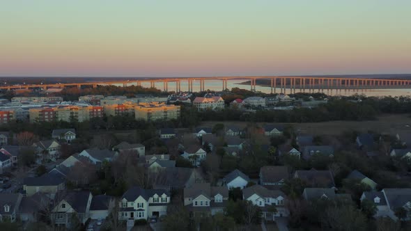 Aerial pull away view of neighborhood surrounding Wando River Bridge at sunset