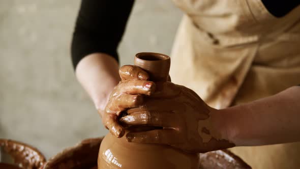 Female Potter's Hands with Red Manicure Working with Wet Clay on a Pottery Wheel Making a Clay