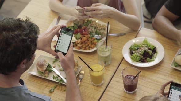 People having meal together looking at their smart phones