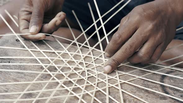 Man's hands weaving bamboo reeds and making a handcrafted hat.Close up of process of making handcraf