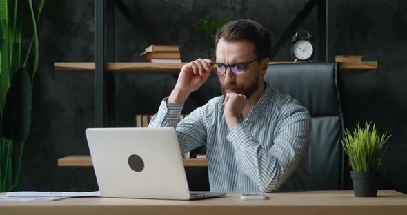 Overworked Businessman Having Stress at Work Sitting at Modern Workplace