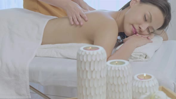 An young Asian woman lying down on a massage table in a spa at the resort during holiday.