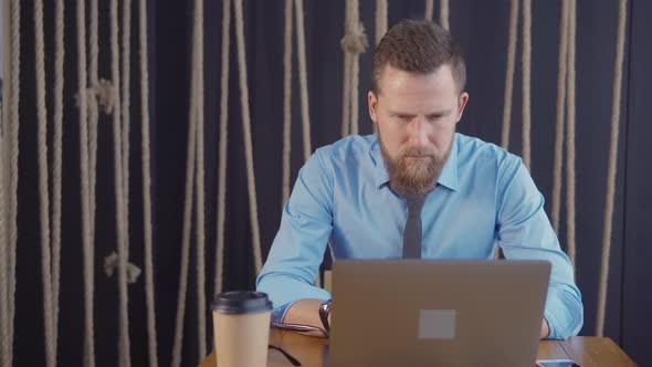 Male Office Worker Is Looking on Display of Laptop Concentrated, Leaning Back