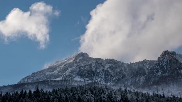 Dramatic fast moving clouds pass over a snowy  mountain,