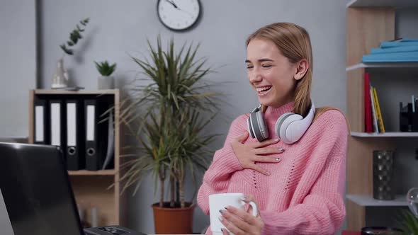 Happy Girl in Modish Sweater Which Revisioning Amusing Videos on Computer