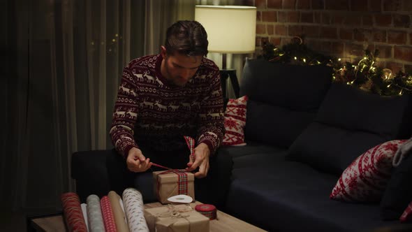 Young adult man packing Christmas gifts. Shot with RED helium camera in 8K